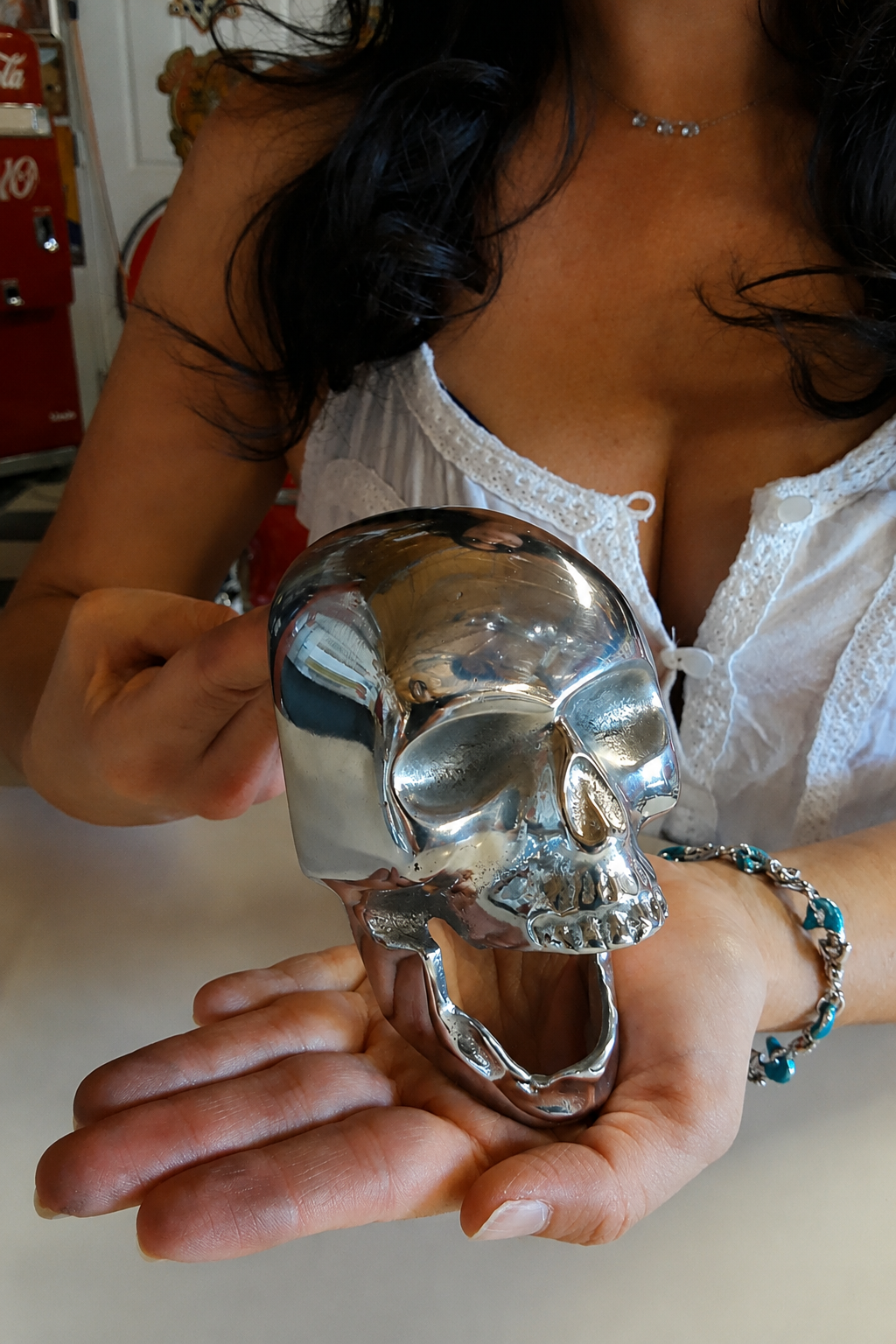 A woman holding a shiny chrome skull in her hands, with a casual background.