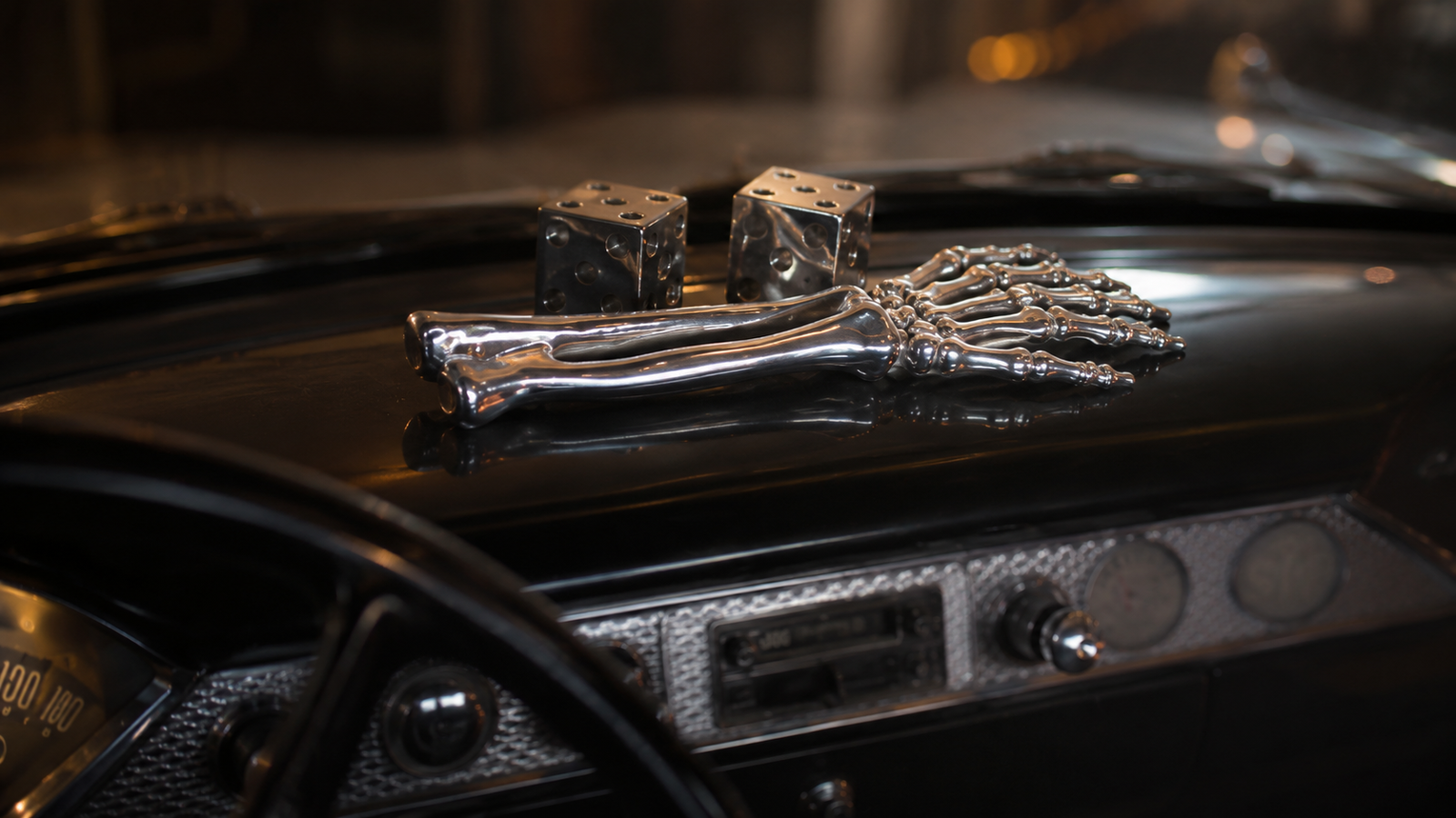 Polished cast-metal skeleton arm displayed on the dashboard of a classic car, shown in a warm cinematic interior with vintage gauges, chrome details, and moody 